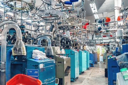 Workshop with modern sock knitting machines at work in textile factory. Industrial production of socksの写真素材
