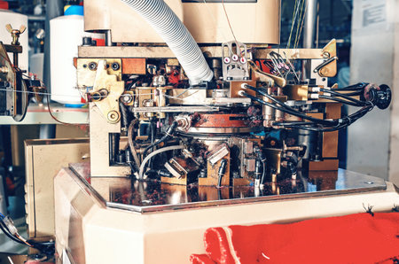 Close-up photo of machine in workshop with exhausted pipe on industrial knitting machine. Knitting factory mechanismsの写真素材