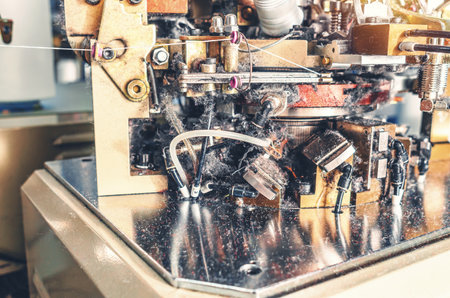 Knitting machine with yarn dust. Close-up of knitting machine with cotton yarn in sock factory