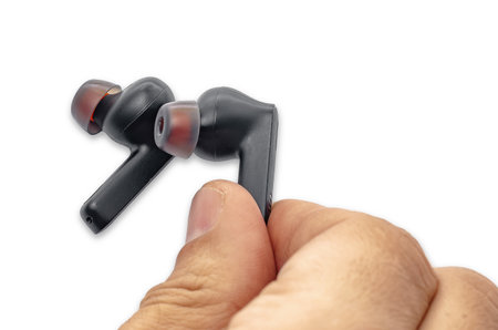 Male fingers holding wireless black headphones on white background, isolated. Used black headphones....