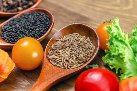 Wooden spoon of cumin seeds close-up. Cumin seeds in spoon on wooden surface. Salad, black sesame...