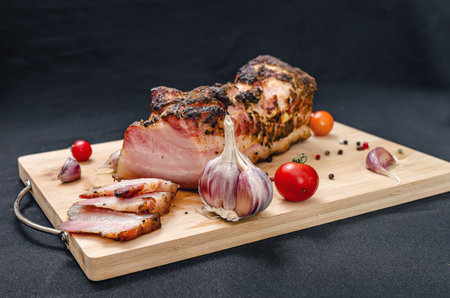 Sliced pork belly. Delicious slices of baked pork belly on wooden board with fresh garlic cloves,...