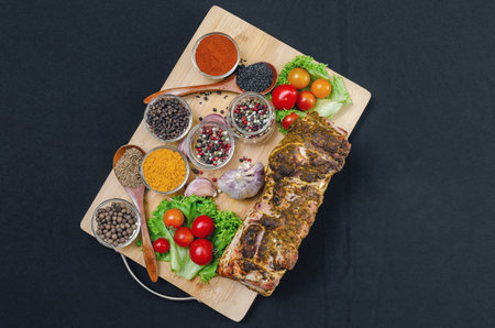 Set of bright spices of turmeric, paprika, various peppers, sesame, cumin, cloves and vegetables including cherry tomatoes, garlic, physalis on textured wooden cutting board. Tasty food.の写真素材