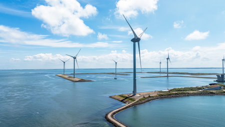 Wind farm in ocean, Holland. Aerial view of windmills on water under cloudy sky. Sustainable...