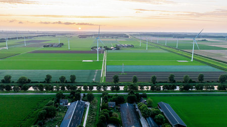 Drone view of wind farm with huge generator turbines during sunset in fields. Windmills, electricity...