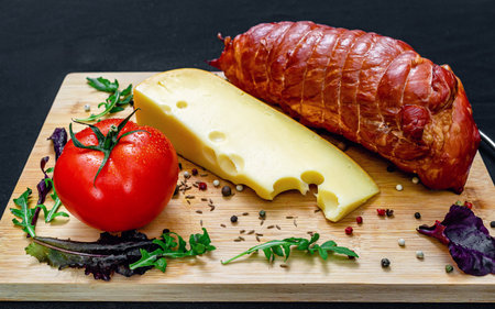 Meat, cheese, vegetables. Restaurant board with cheese, roasted pork, tomatoes and peppers, served with salad and greens. Healthy protein menu. Black background. Side viewの写真素材