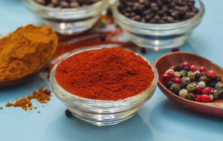 Spices and seasonings. Orange paprika in bowl on light blue background. Texture of food seasonings close-up.の写真素材