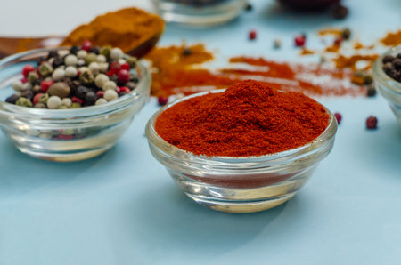 Spices and seasonings. Orange paprika in bowl on light blue background. Texture of food seasonings close-up. Vibe of spices in cooking.の写真素材