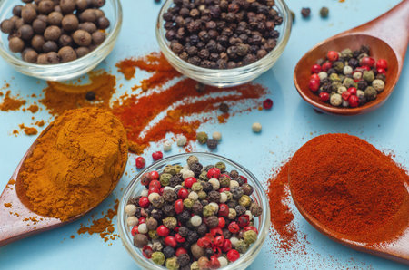 Aromatic spices and seasonings. Bright colors of Indian spices. Colored peppers in bowl on light blue background. Texture of food seasonings close-up. Vibe of spices in cooking.の写真素材
