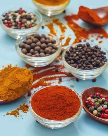 Aromatic spices and seasonings. Bright colors of Indian spices. Orange paprika in bowl on light blue background. Texture of food seasonings close-up. Atmosphere of spices in cooking.の写真素材