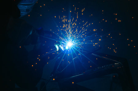 Welding process with sparks. Welding metal frame in workshop, creating sparks, light and smoke in...