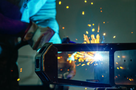 Man worker working with metal product and welding it with welding machine in workshop. Small business manufacturing concept.. Close-up.の写真素材