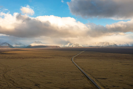 Drone view of long straight road through textured autumn plains of northeastern Iceland amidst...