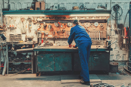 Professional worker in blue work uniform and orange protective gloves in production workshop. Image symbolizes production processes and skilled female employment in industry.の写真素材
