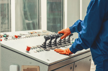 Hands of industrial worker in blue protective uniform working with control panel with joysticks and buttons. Concept of machine control, industrial automation, safety.の写真素材