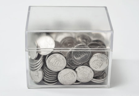 Transparent plastic box with coins isolated on white background. Concept of storage, donation, money...