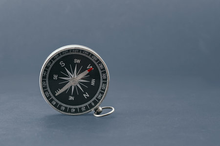 Compass with black dial isolated on gray background. Navigation device with arrows indicating...