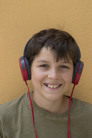 Smiling teen boy posing outdoors. Looking at camera with headphonesの写真素材