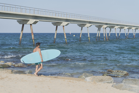 Young attractive surfer holding his surfboard at the beachの写真素材