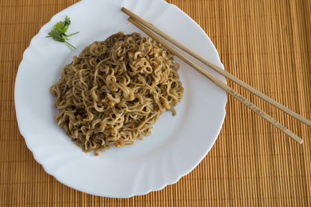 Yakisoba / noodles with beef in rectangle plate with bamboo sticks on a tableの写真素材