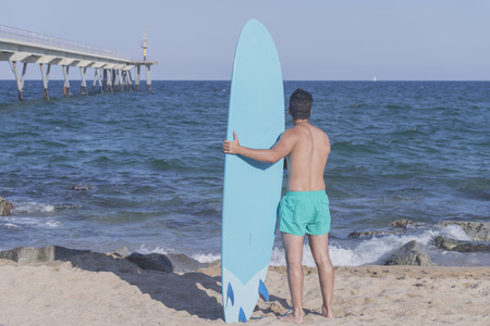 Surfer holding his blue surfboard ( from behind )の写真素材