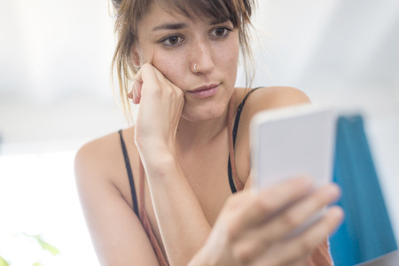 Happy young businesswoman using mobile phone in officeの写真素材