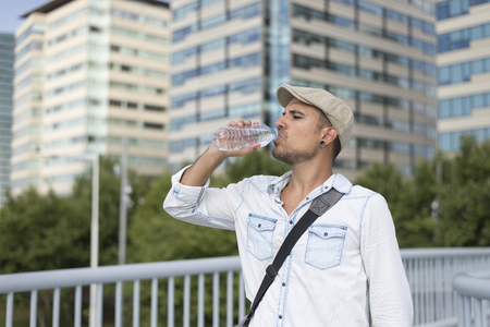 Young and masculine man drinking a water outsideの写真素材