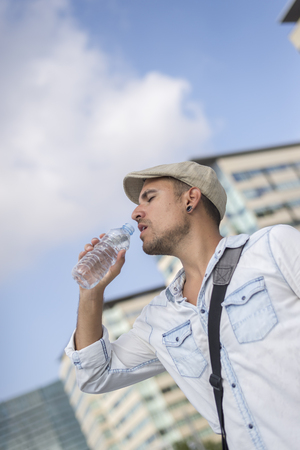 Young and masculine man drinking a water outsideの写真素材