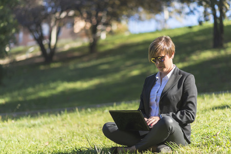 Businesswoman Sitting In Field Using Laptopの写真素材