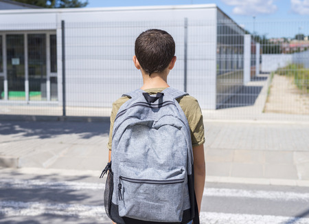Teenage school boy with a backpack on his back walking to schoolの写真素材