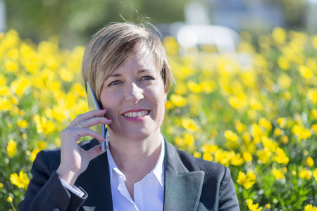 Smilie executive talking on phone looking at camera on the streetの写真素材