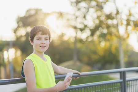 Portrait of a teenager smiling using his smartphone on a basketball courtの写真素材