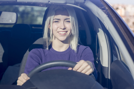Beautiful Smiling woman driving car, attractive girl sitting in automobile, outdoors summer portrait.の写真素材