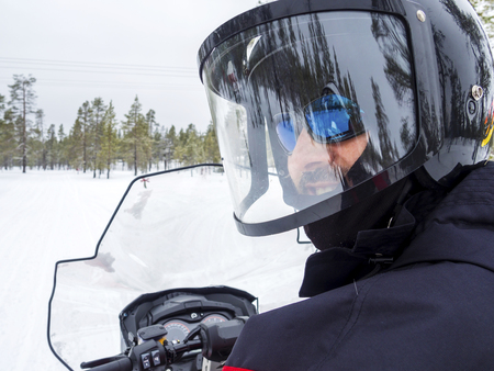 Happy smiling man riding snowmobileの写真素材