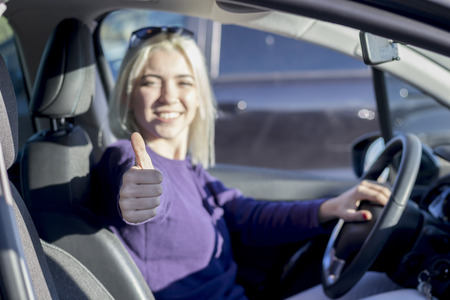 Beautiful woman inside a car showing thumbs up
