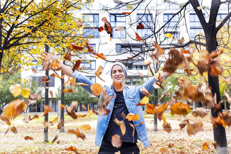Young man throwing autumn leaves in the air
