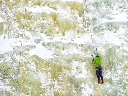 Caucasian man wearing blue jacket climbing ice wallの写真素材