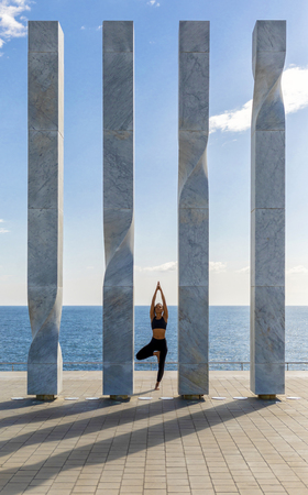 Portrait of young woman doing yoga exercise on seasideの写真素材