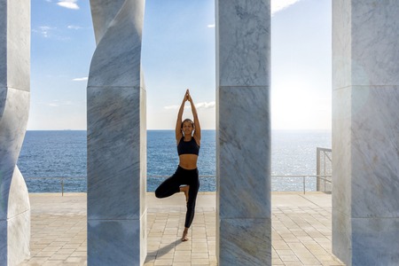 Portrait of young woman doing yoga exercise on seasideの写真素材