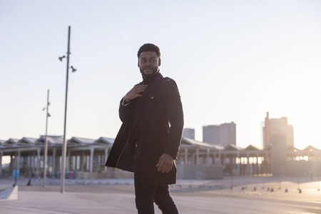 Rear view of a black young bearded man walking outdoors while looking away