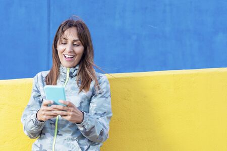 Woman standing and using a smart phone in the street in a sunny day