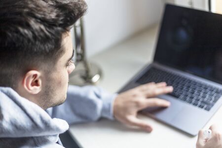 Rear view of a young man working with laptop on desktopの写真素材