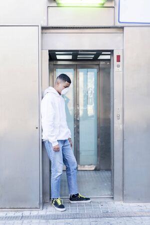 Sick man wearing protective facial mask against transmissible infectious diseases and as protection against the coronavirus in public place.の写真素材