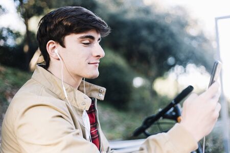 Young man using mobile phone while sitting outdoors