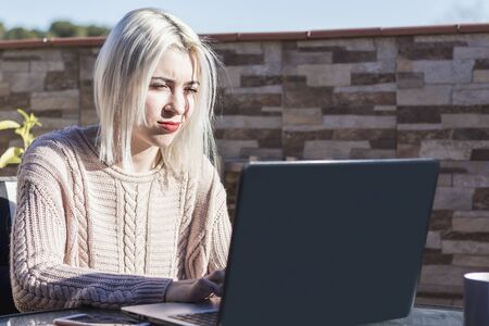 Student girl using laptop while sitting outdoors at home terrace.の写真素材
