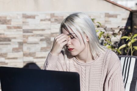 Student girl using laptop while sitting outdoors at home terrace.の写真素材
