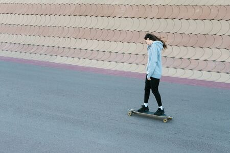 Teenage girl skating on a longboard in a city park in a sunny dayの写真素材