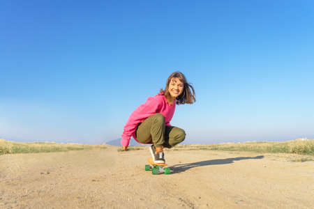 Young woman with pink jersey skateboarding in a footpathの写真素材