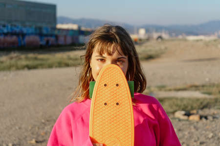 Closeup of a female teen holding a skateboard outdoorsの写真素材