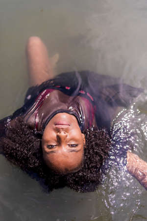 Beautiful afro woman into water while looking camera